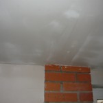 Вид на оштукатуренную поверхность потолка в районе кирпичной кладки