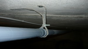 Монтаж канализационной трубы на потолок при помощи металлической ленты 