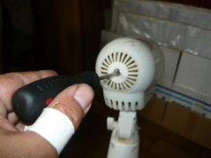 Отвинчивание центрального винта на корпусе напольного вентилятора